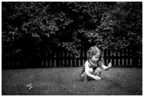 Black and white lifestyle photography shot of young child picking dandelions