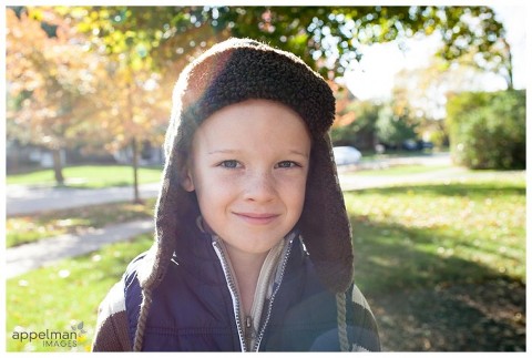 Boy in hat in Naperville family candid photography session with sun flare