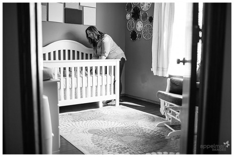 Mommy in little baby girl room smiling at baby in crib by Naperville and Chicago family photographer