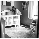 Mommy in little baby girl room smiling at baby in crib by Naperville and Chicago family photographer