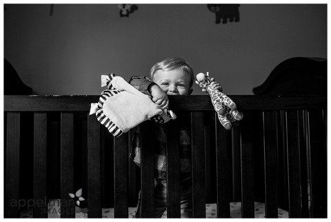 Bright little baby boy in his crib with toys black and white